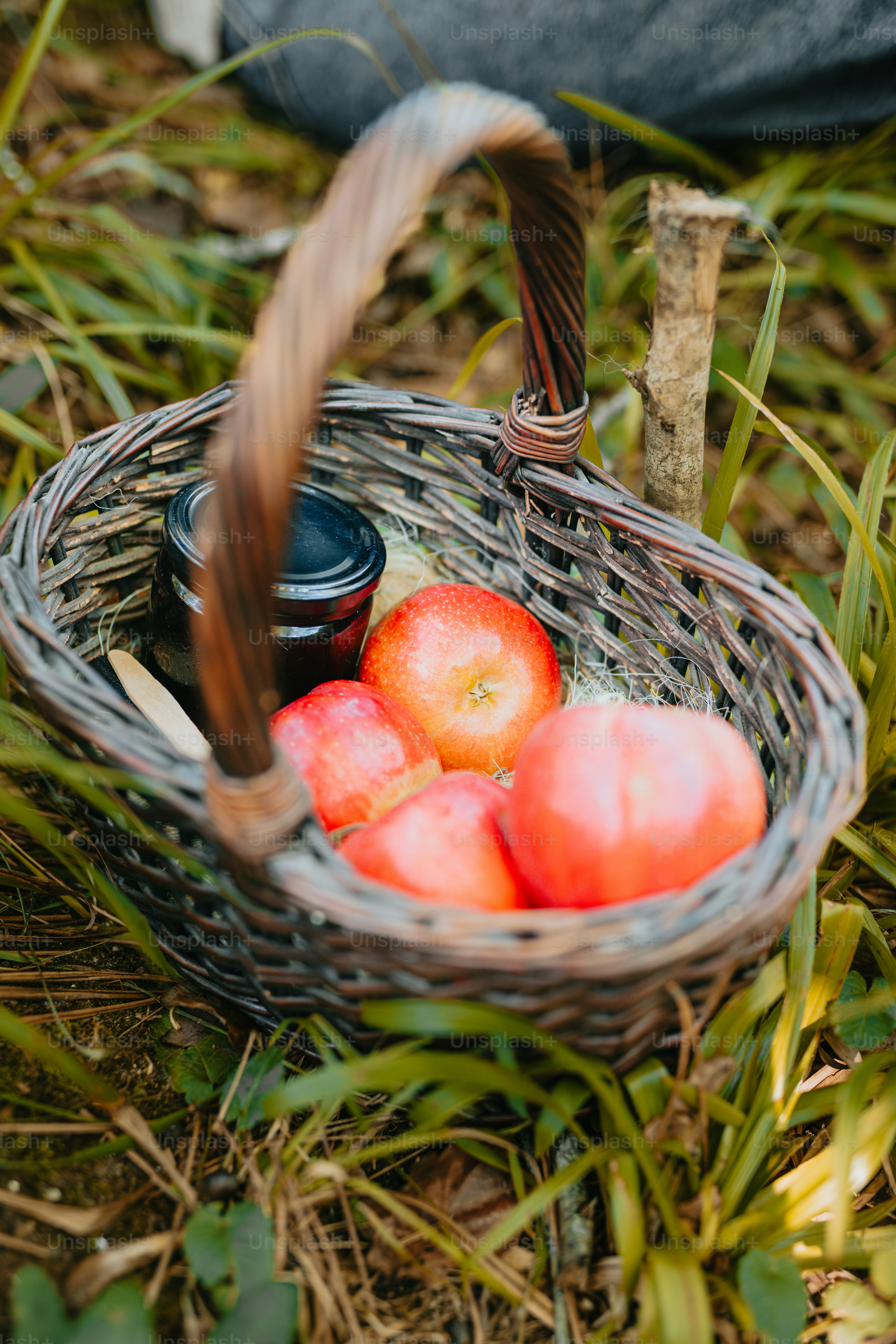 A basket filled with apples sitting on top of a grass covered field ...