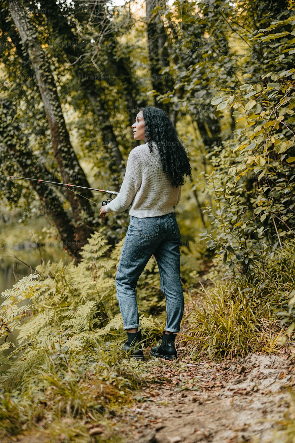 Una mujer parada en un sendero en el bosque