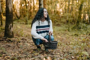a woman kneeling in the woods holding a basket