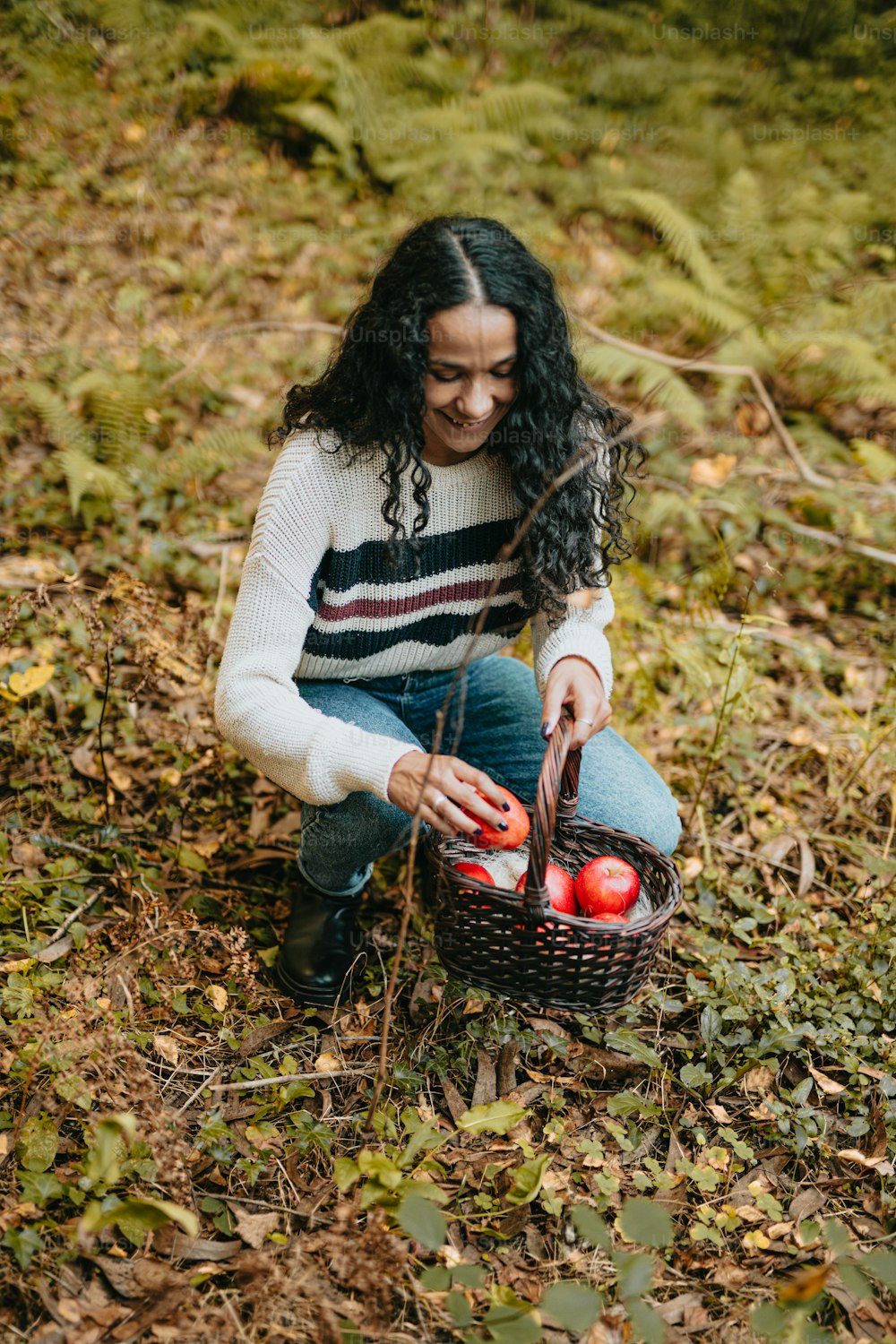 a woman sitting on the ground with a basket of apples