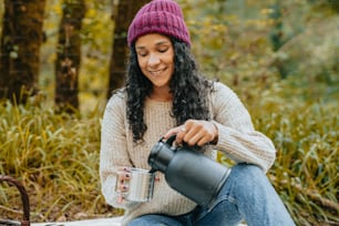 a woman sitting on the ground with a cup of coffee