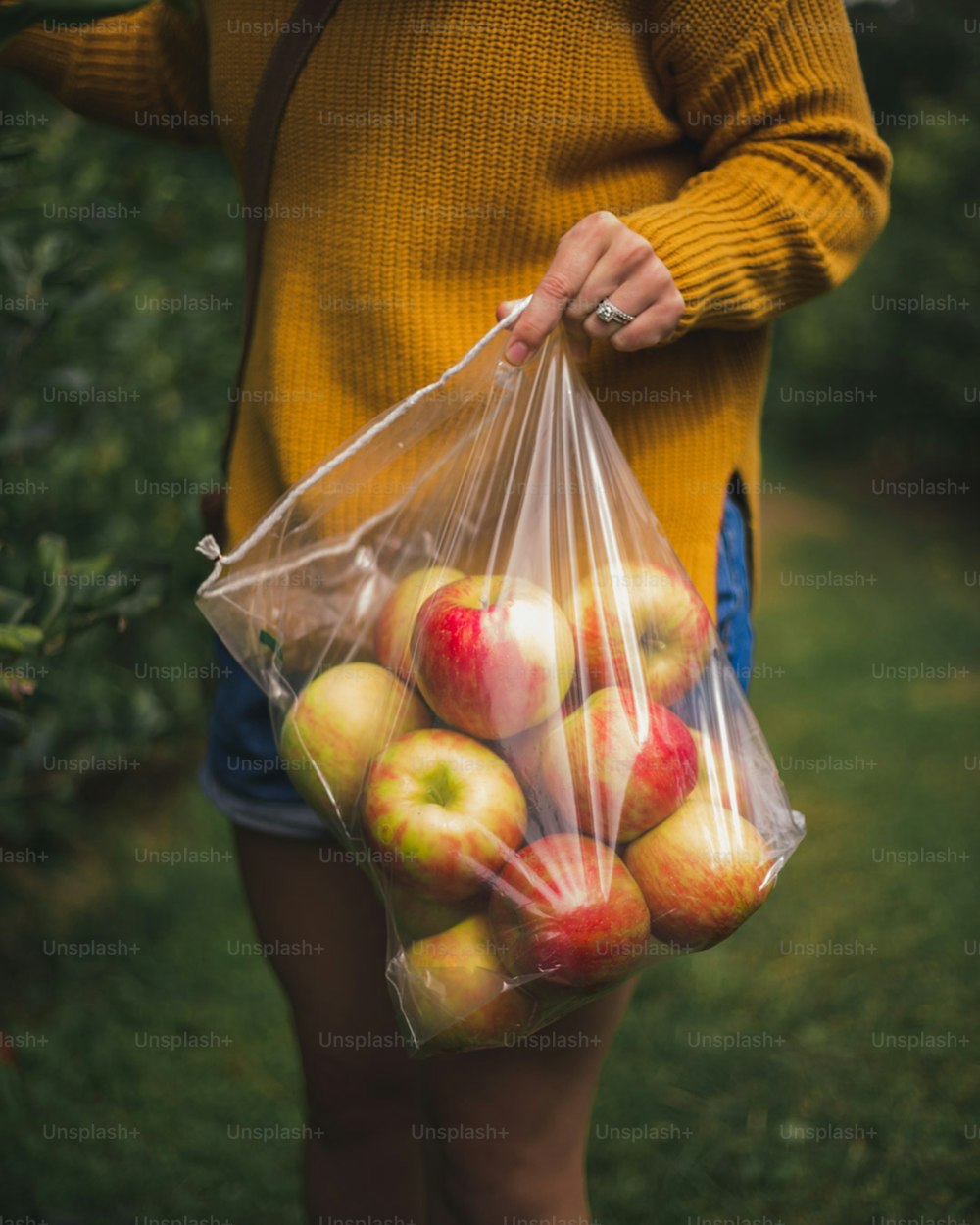 a woman holding a bag of apples in a field