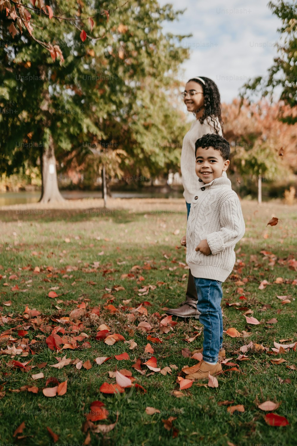 a boy and a girl standing in a field of leaves
