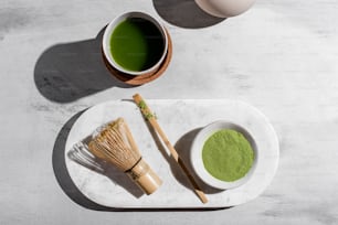 una taza de té verde junto a un batidor y un batidor