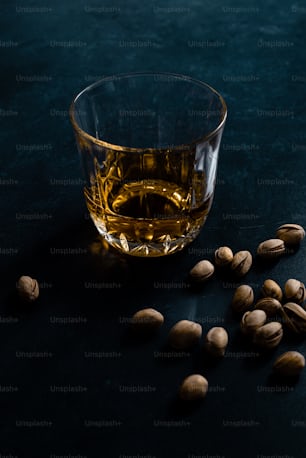 a glass of whiskey and nuts on a table