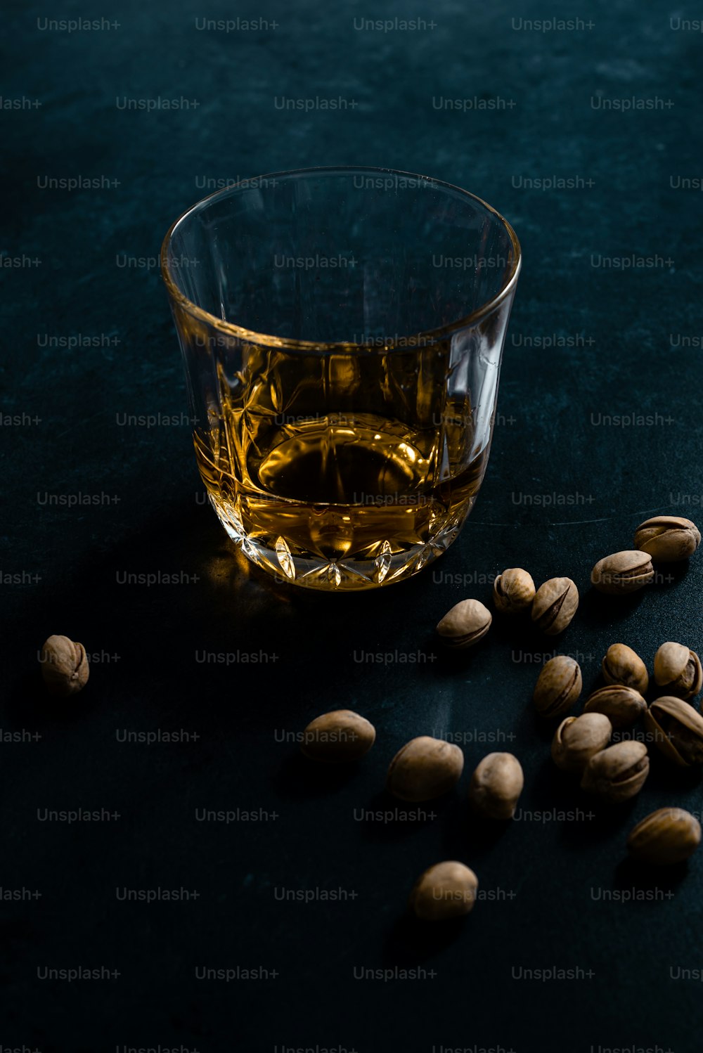 a glass of whiskey and nuts on a table