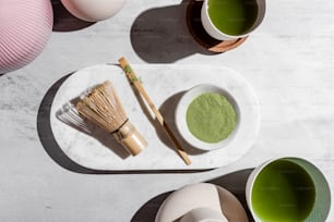 a table topped with bowls and cups filled with green tea