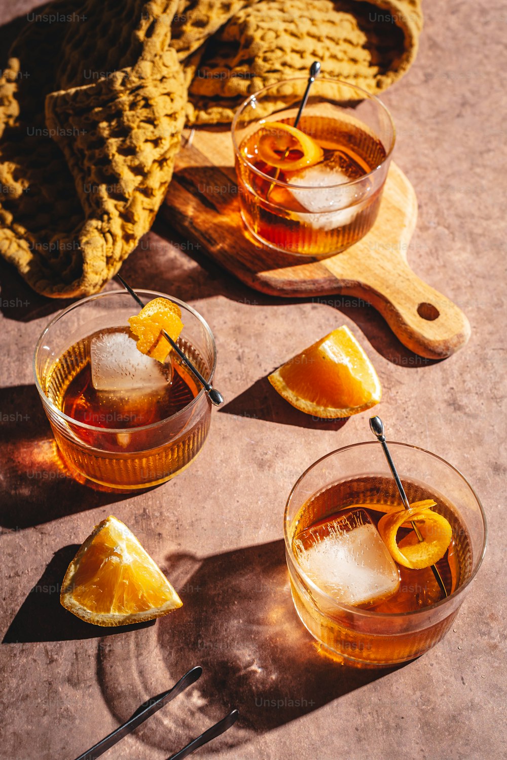 a couple of glasses filled with liquid next to a wooden cutting board