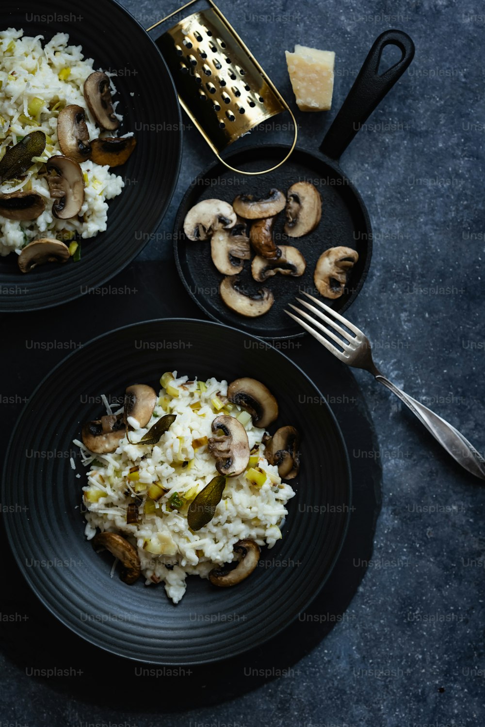 two black plates with rice and mushrooms on them