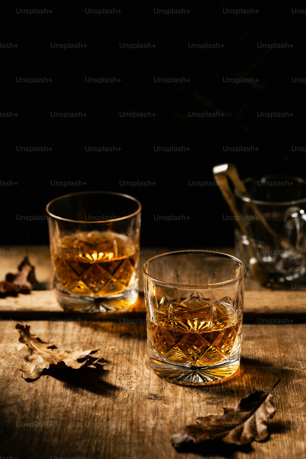 Dos vasos de whisky sobre una mesa de madera