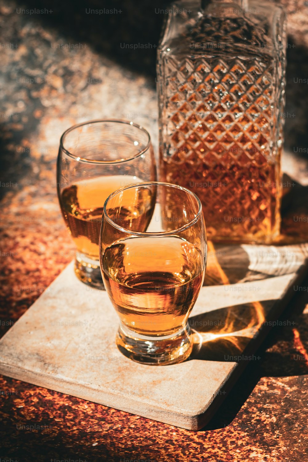 two glasses of whiskey sitting on a cutting board
