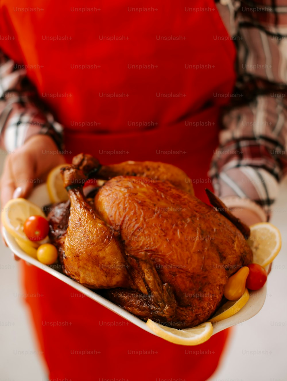 a person in an apron holding a plate with a turkey on it