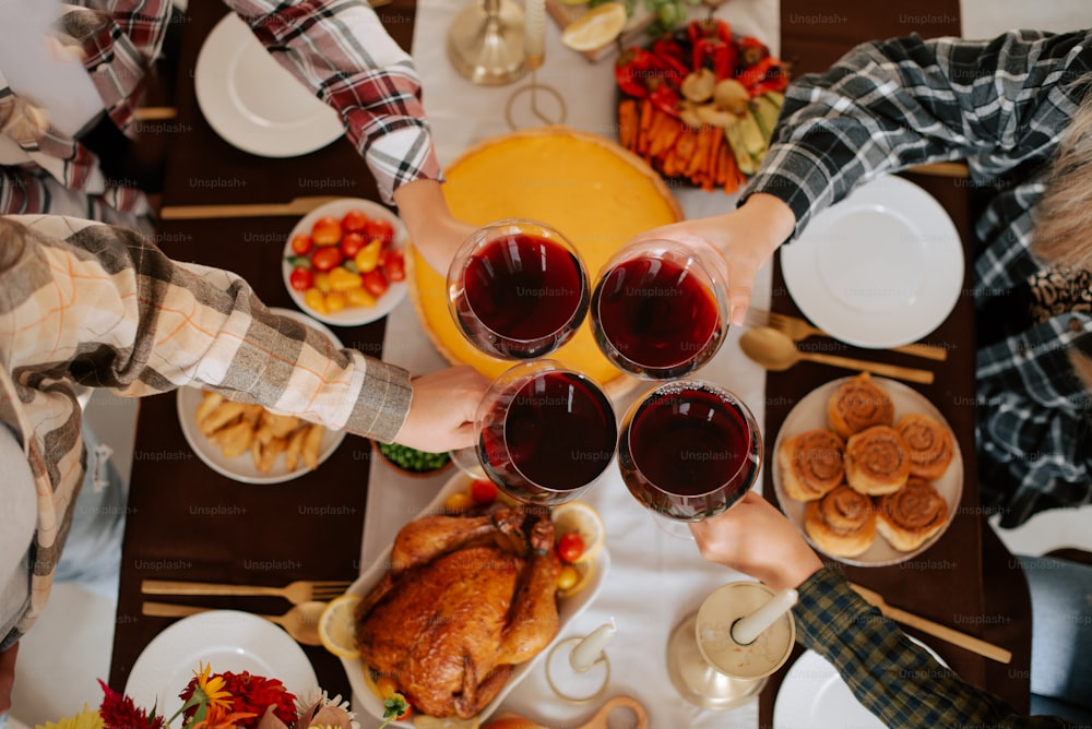 Um grupo de pessoas segurando taças de vinho em um jantar de Ação de Graças