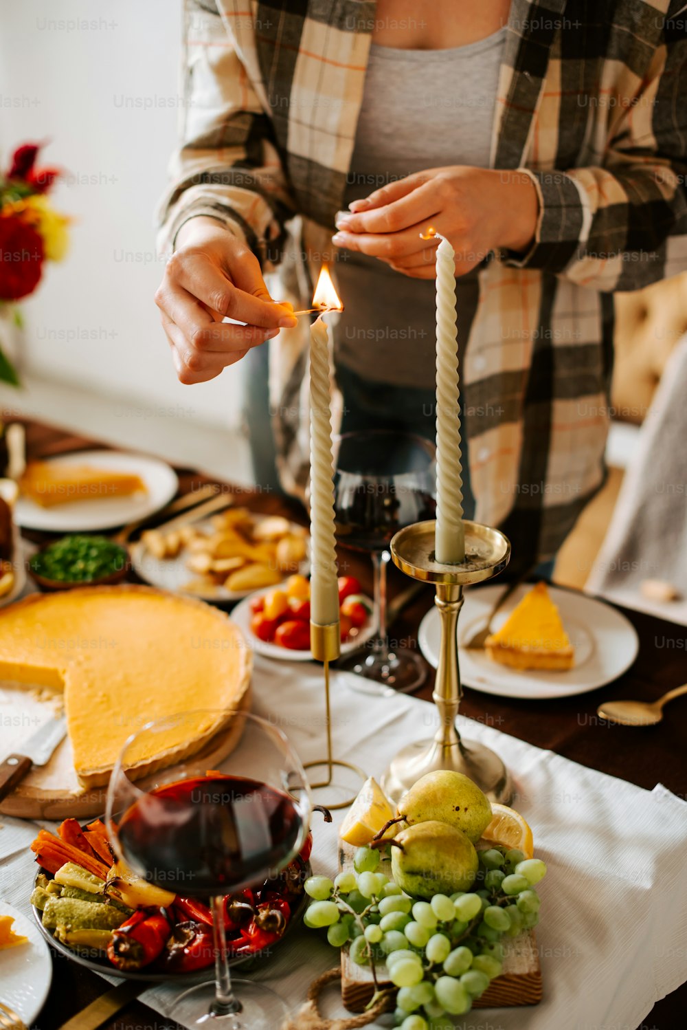 a person lighting a candle on a table with food