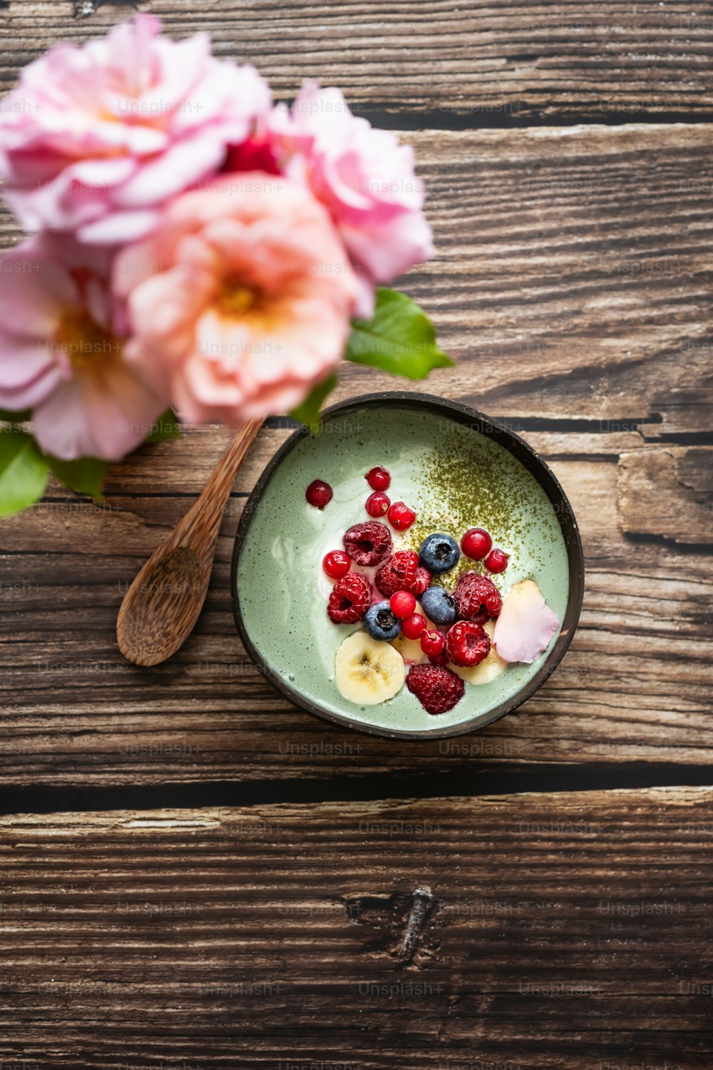 a bowl of berries and bananas on a wooden table