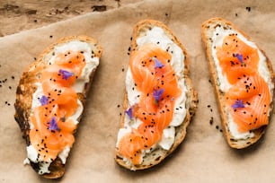 three pieces of bread with cream cheese and salmon on them