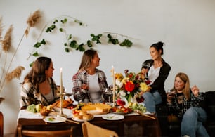 a group of women sitting around a table with food