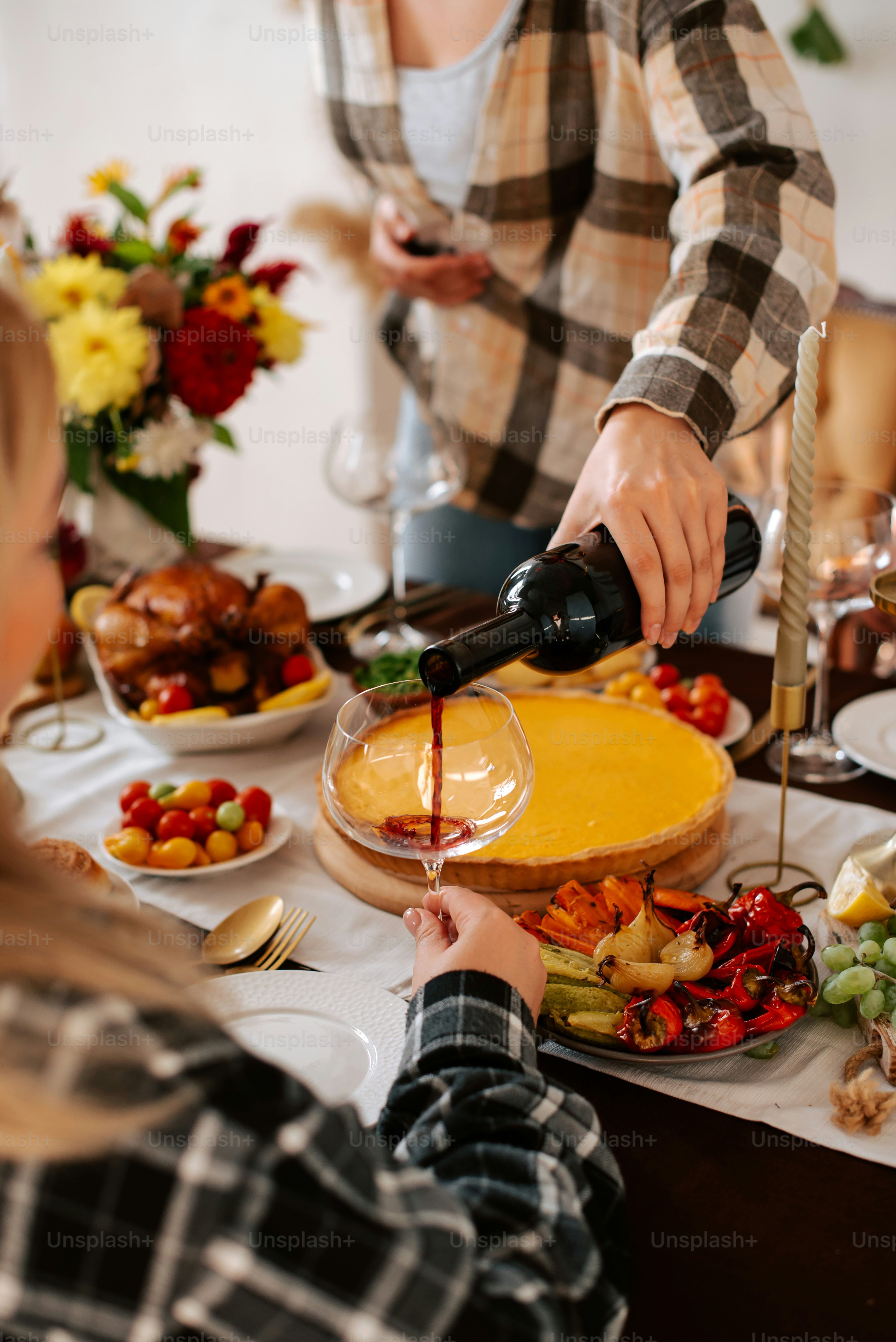 a woman pouring a glass of wine at a table full of food