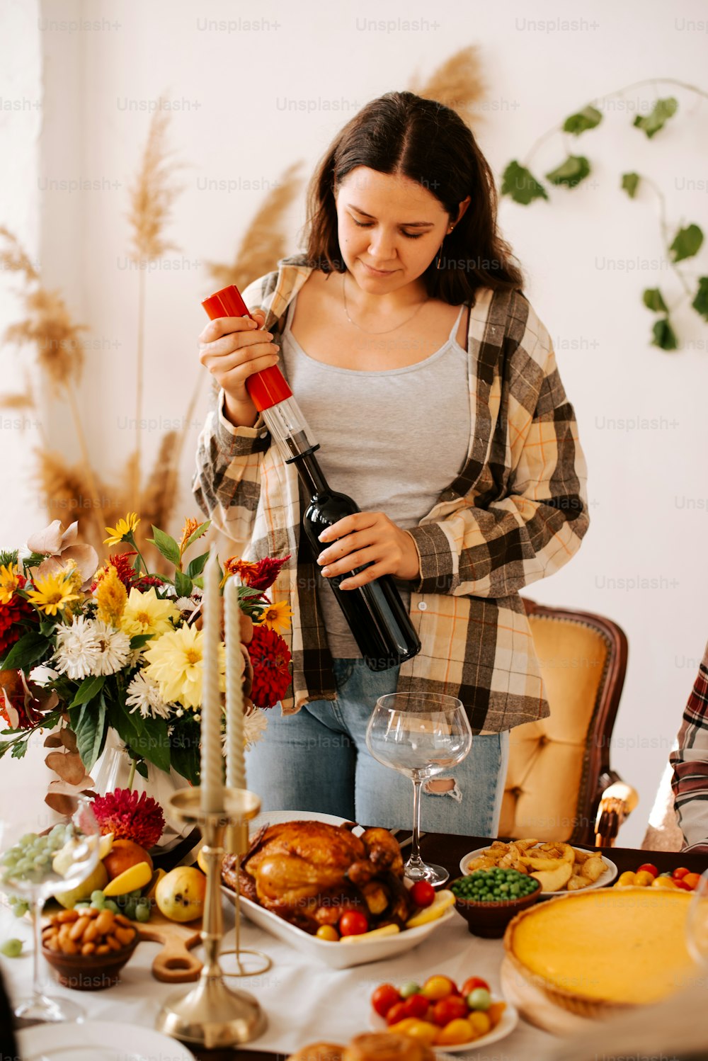 a woman pouring a glass of wine in front of a table full of food