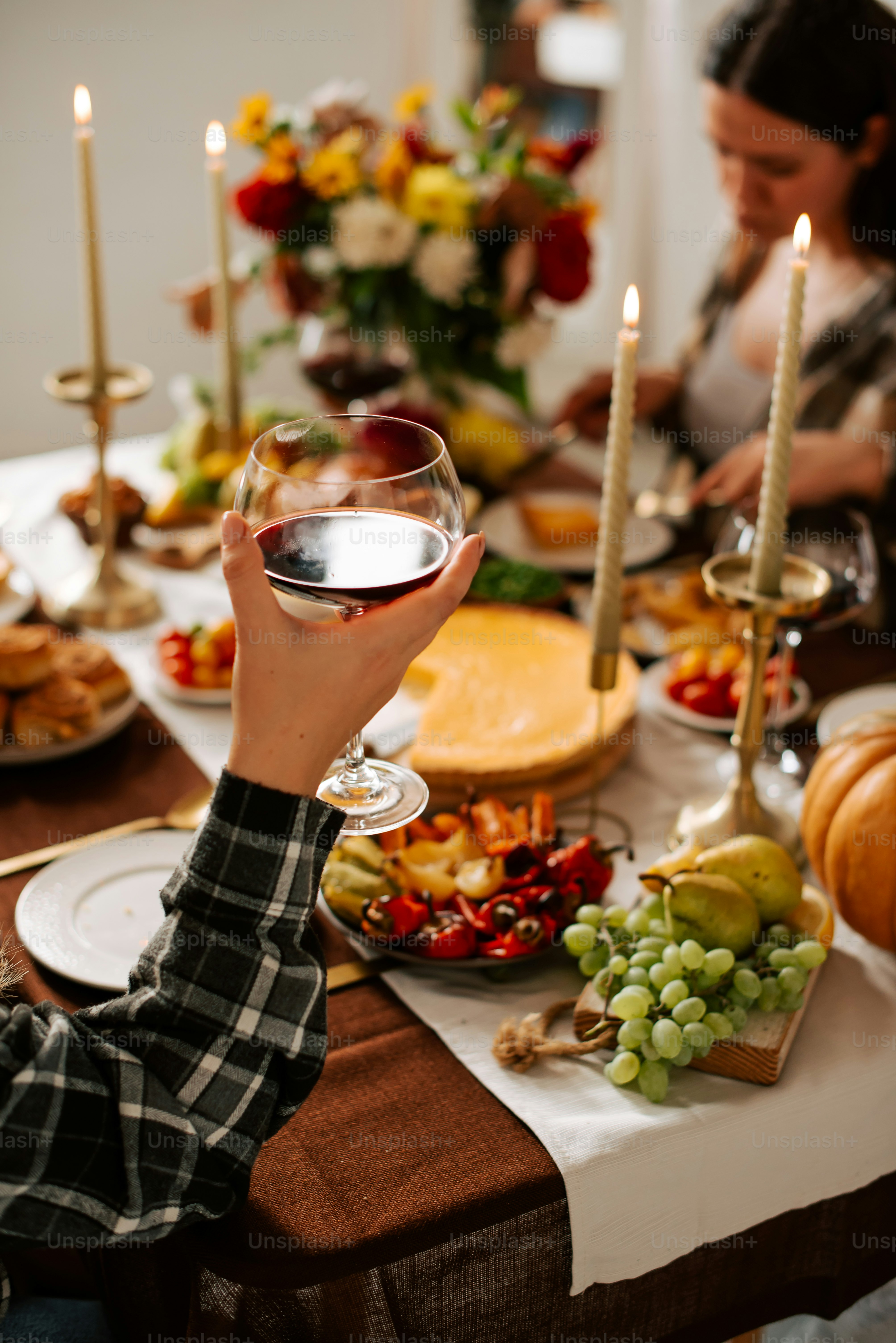 a woman holding a glass of wine in front of a table full of food
