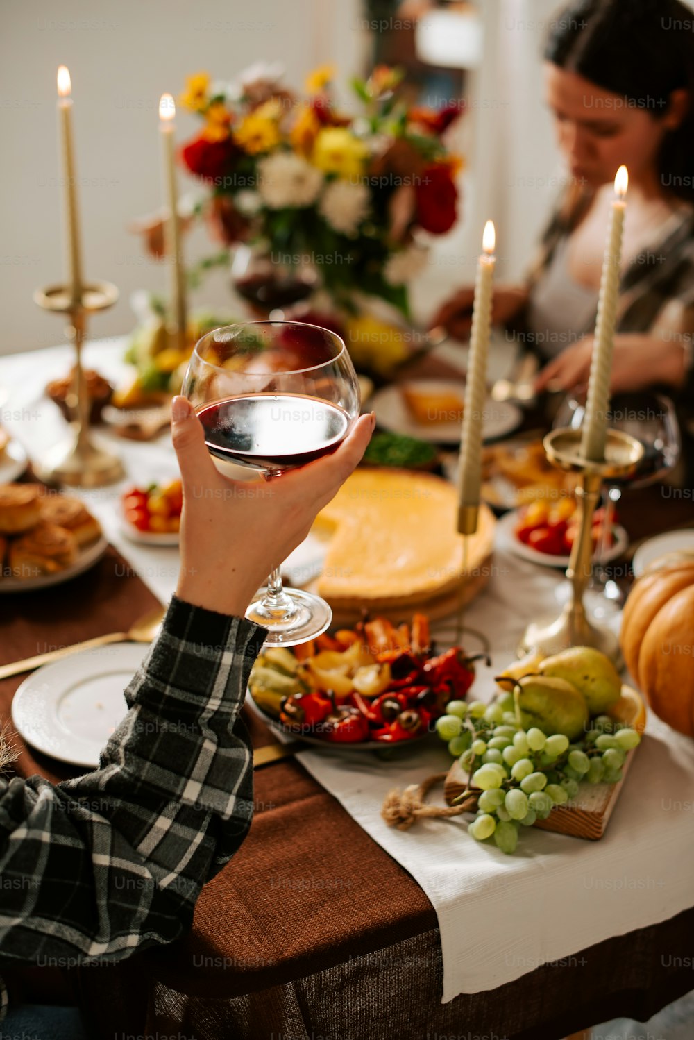a woman holding a glass of wine in front of a table full of food
