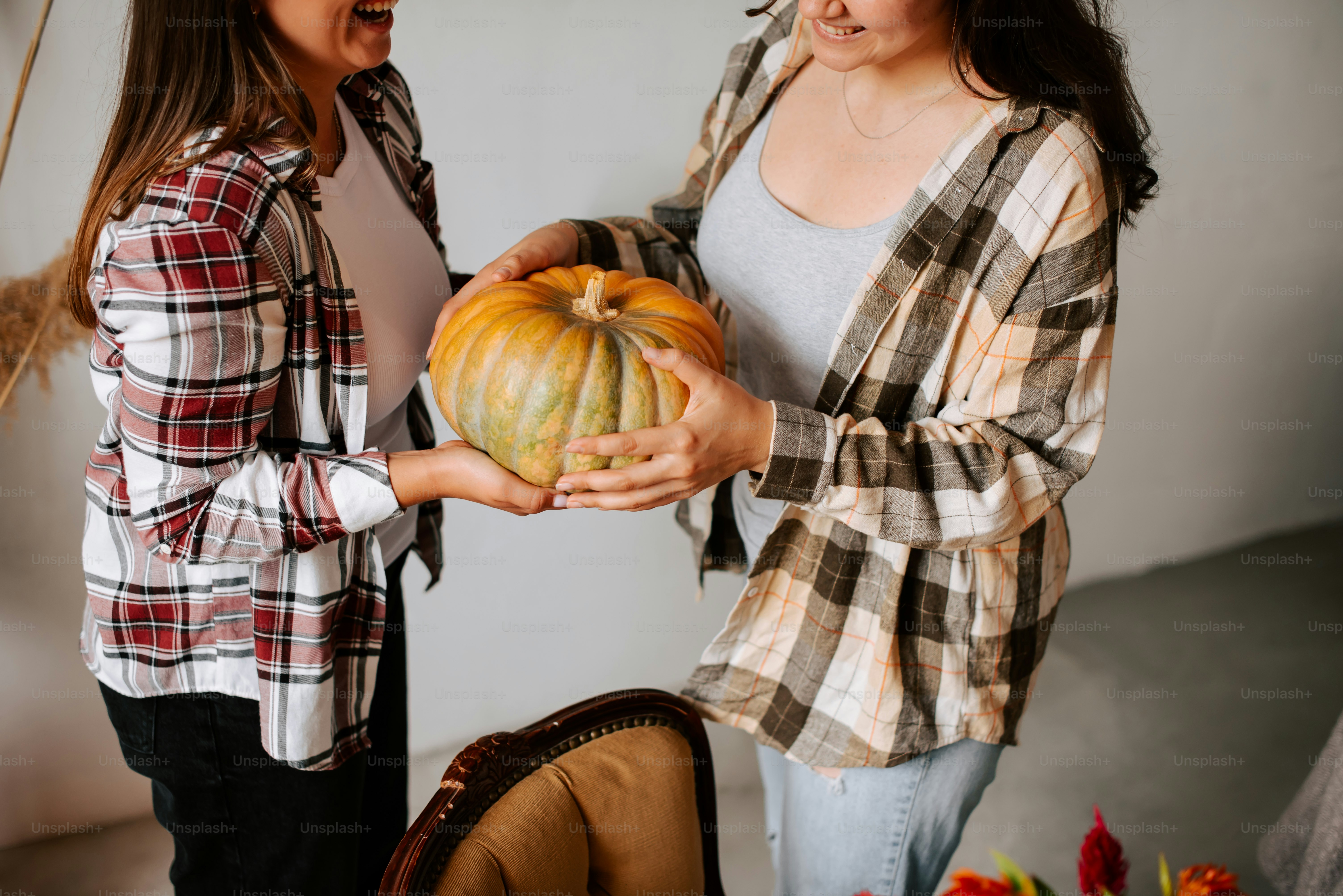 two women holding a large pumpkin in their hands