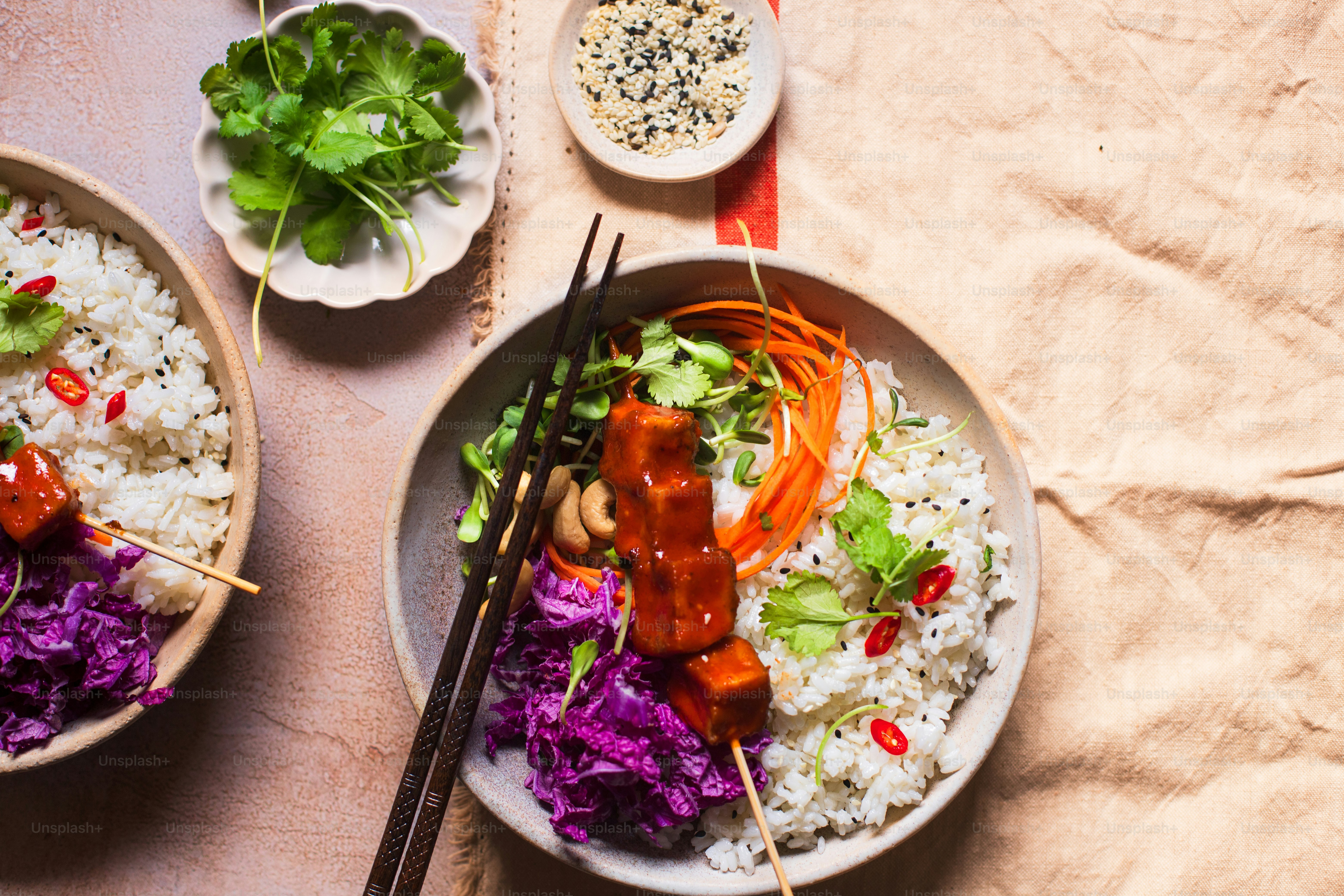 two bowls of food on a table with chopsticks