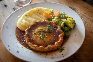 a white plate topped with food on top of a wooden table