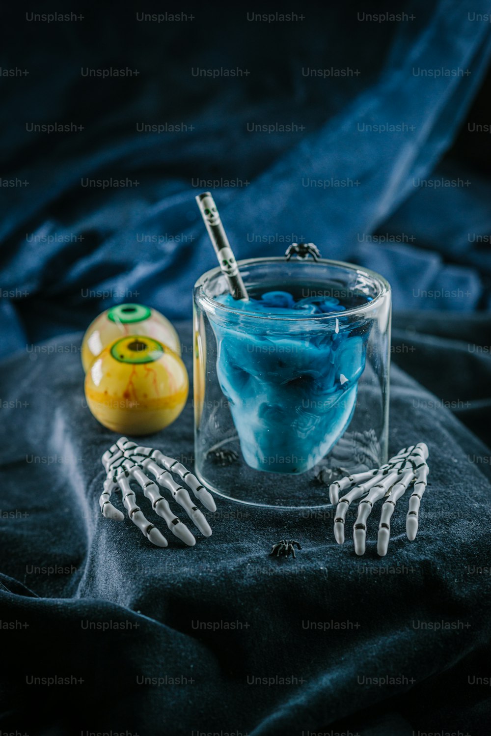 uma mão de esqueleto segurando uma escova de dentes ao lado de um copo de líquido azul