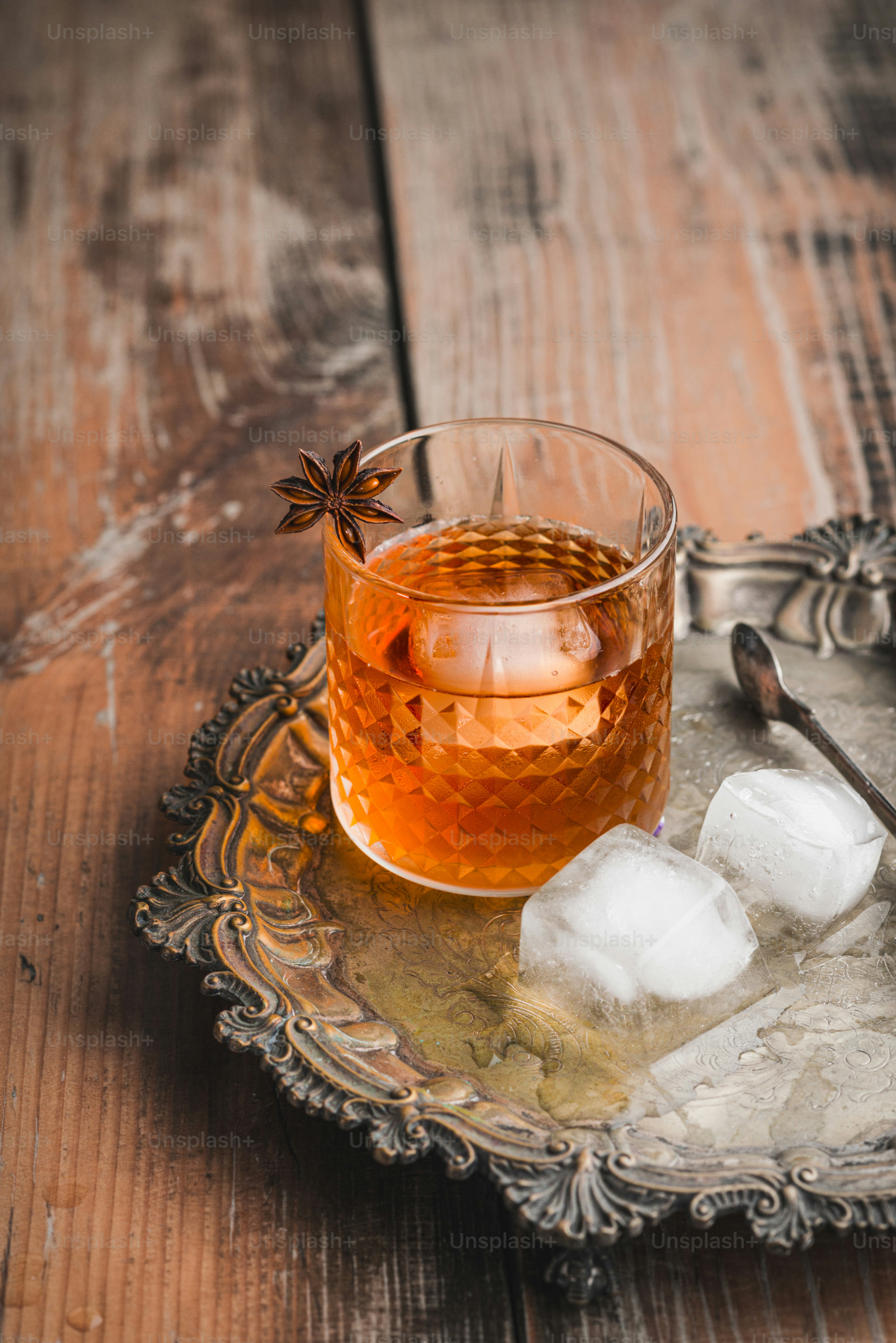 a glass of tea with ice cubes on a tray