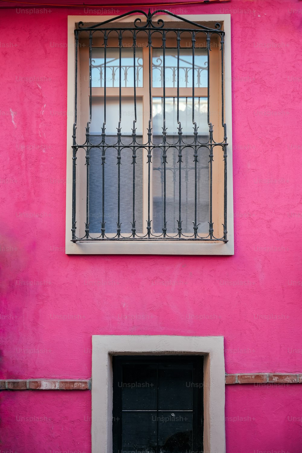 um edifício rosa com uma porta e janela pretas