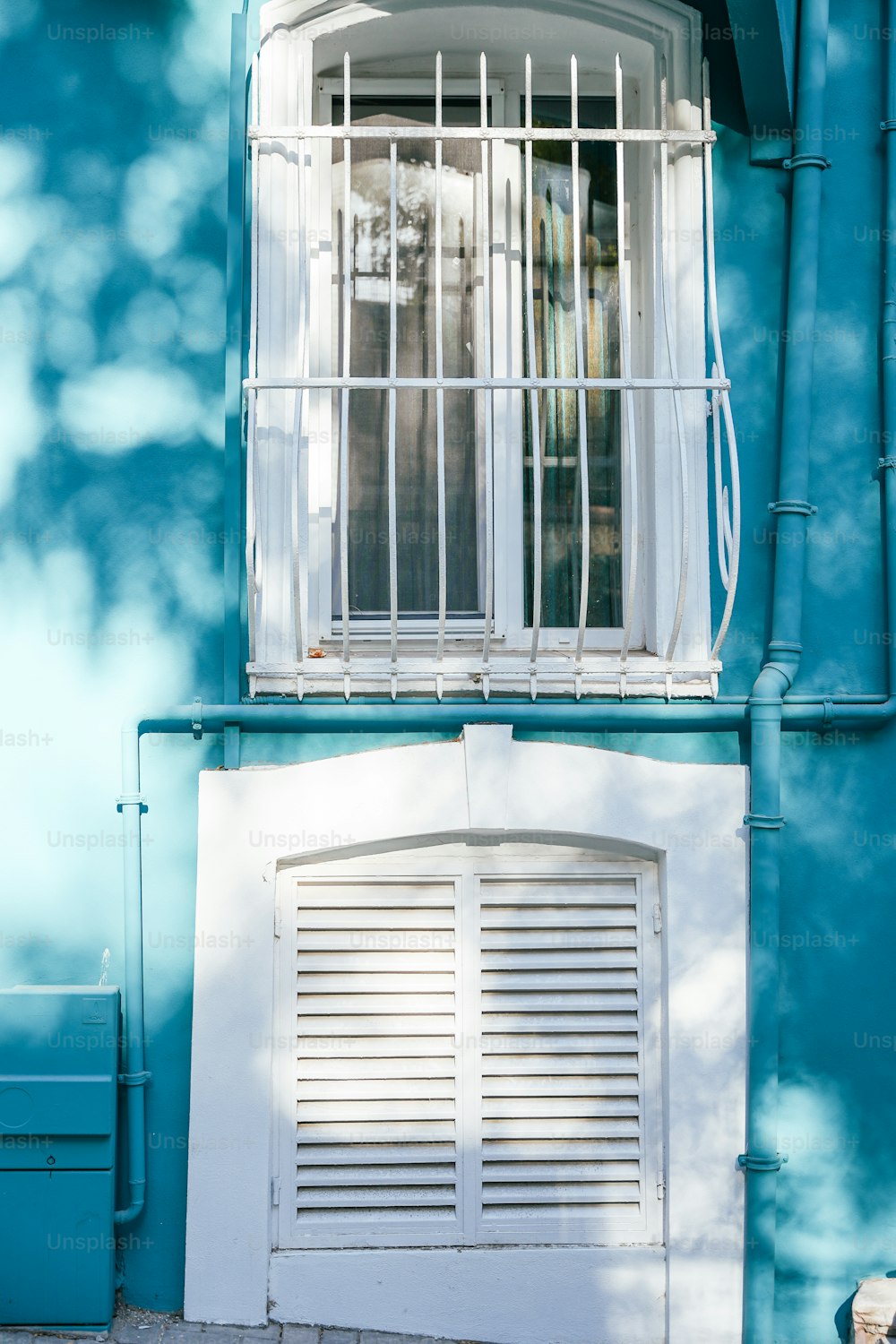 a blue building with a white window and shutters