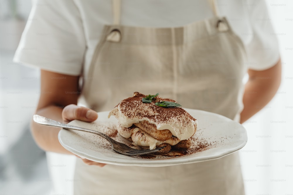 a person holding a plate with a dessert on it