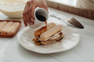 Una persona vertiendo jarabe en un sándwich en un plato