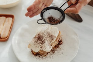Eine Person gießt Kaffee in ein Dessert auf einem Teller