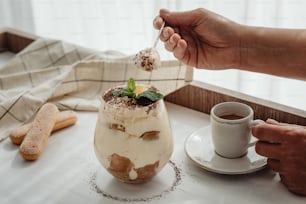 a person holding a spoon over a dessert in a glass