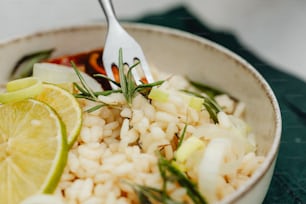 a close up of a bowl of food with rice and lemon