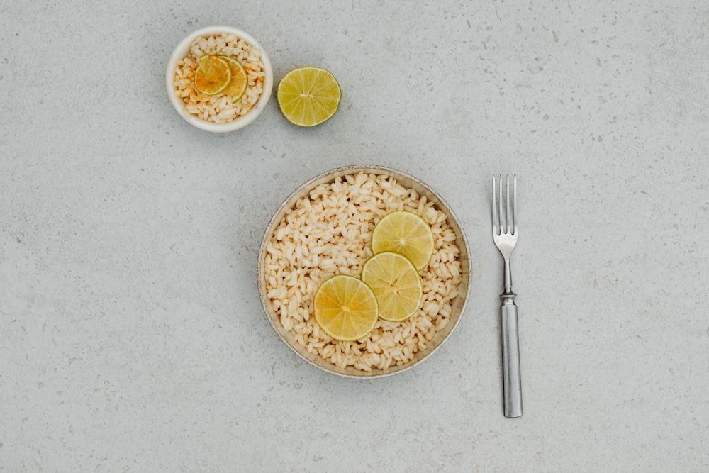 a bowl of rice with lemon slices and a fork
