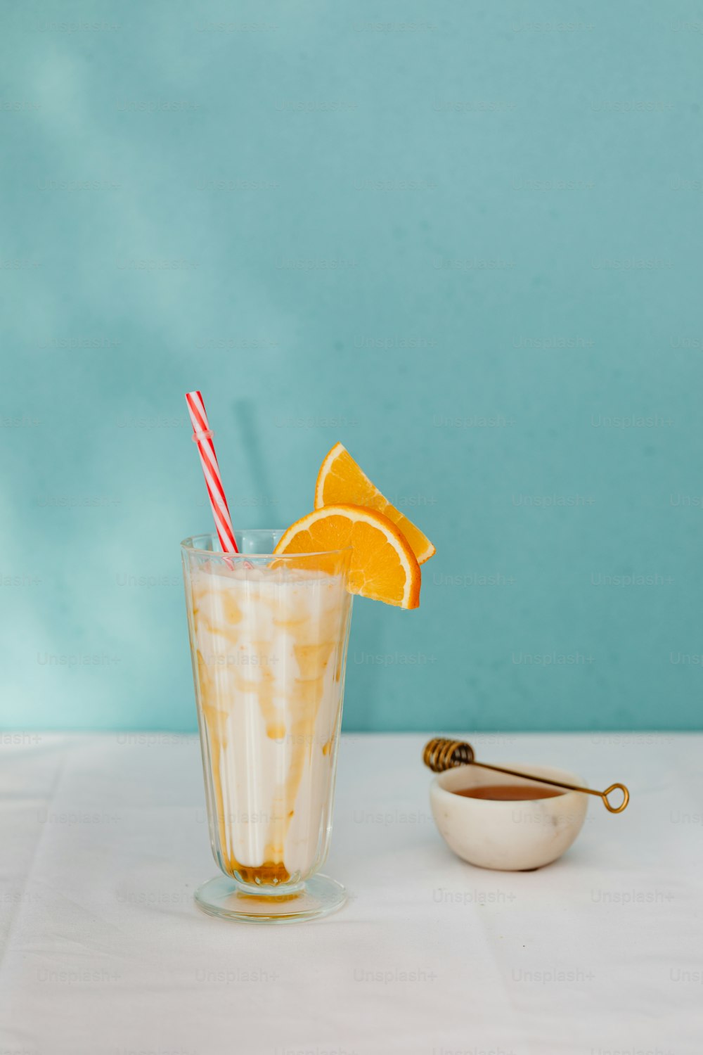 a glass of orange juice with a straw and a bowl of orange slices