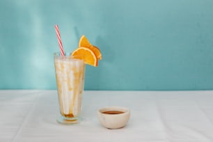a glass of iced coffee with orange slices and a straw