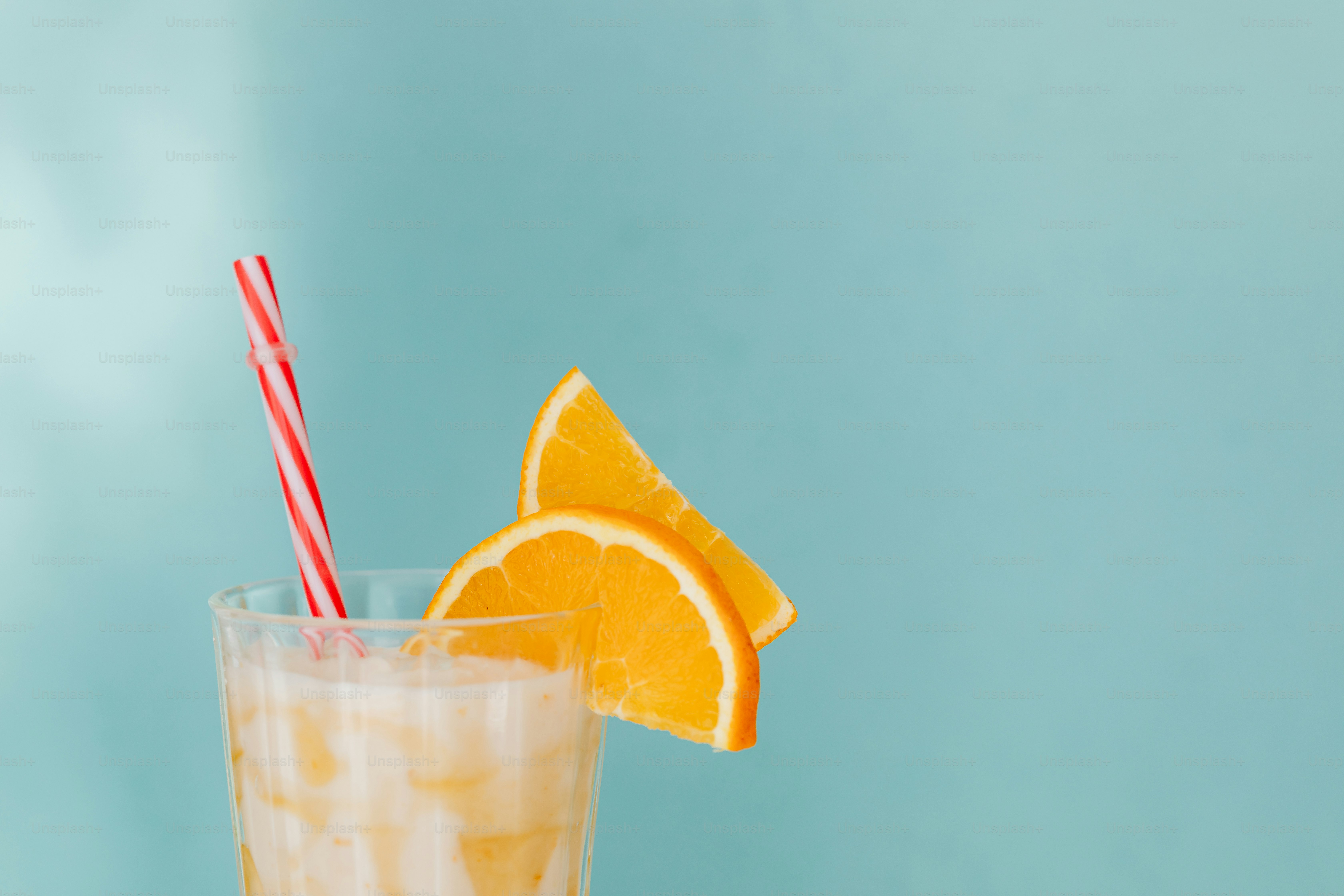 a glass of orange juice with a straw