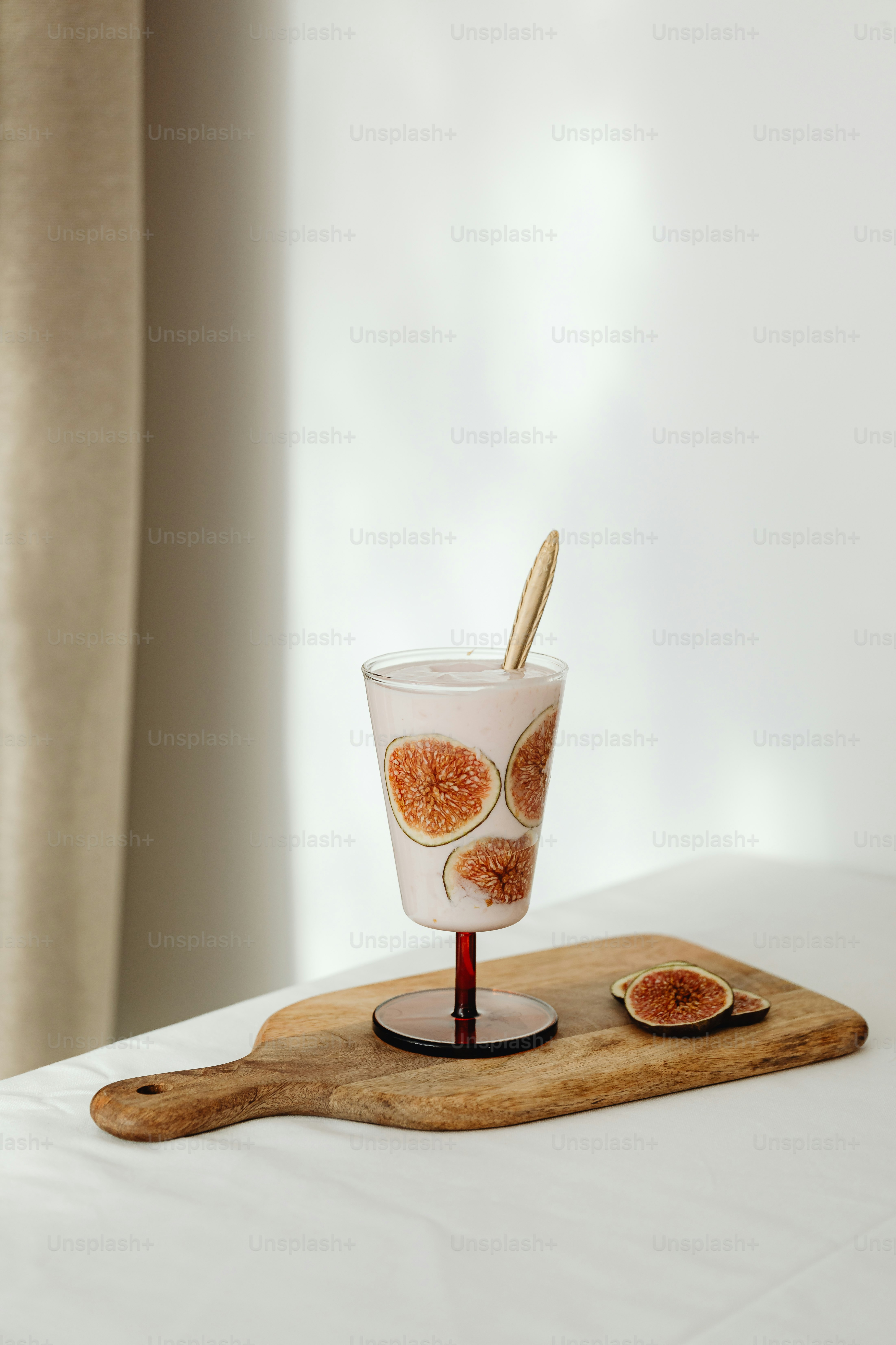 a glass with a spoon in it sitting on a cutting board