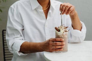 a woman is holding a drink with whipped cream and chocolate