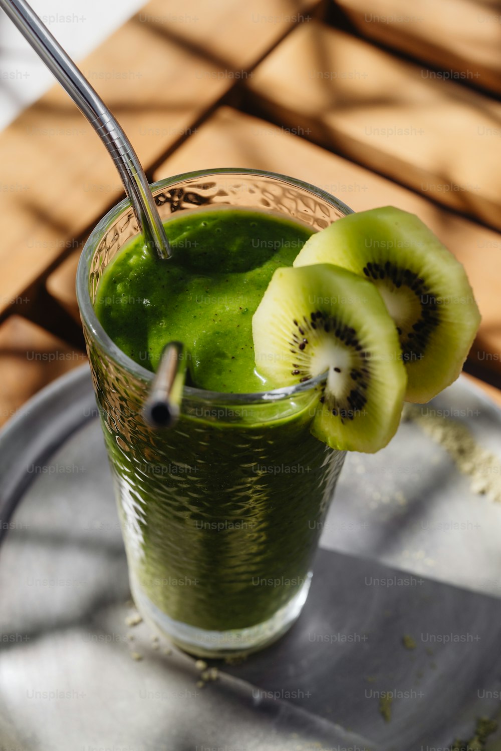 a glass of green smoothie with kiwi slices on the rim