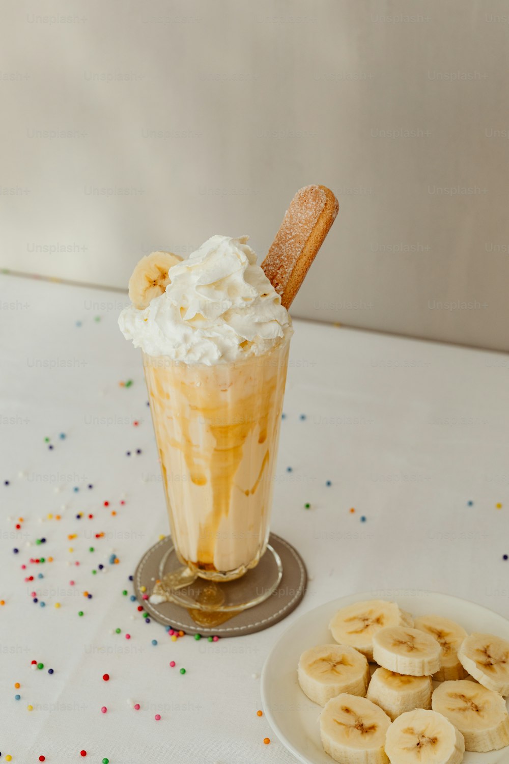 a cup of ice cream with banana slices on a plate