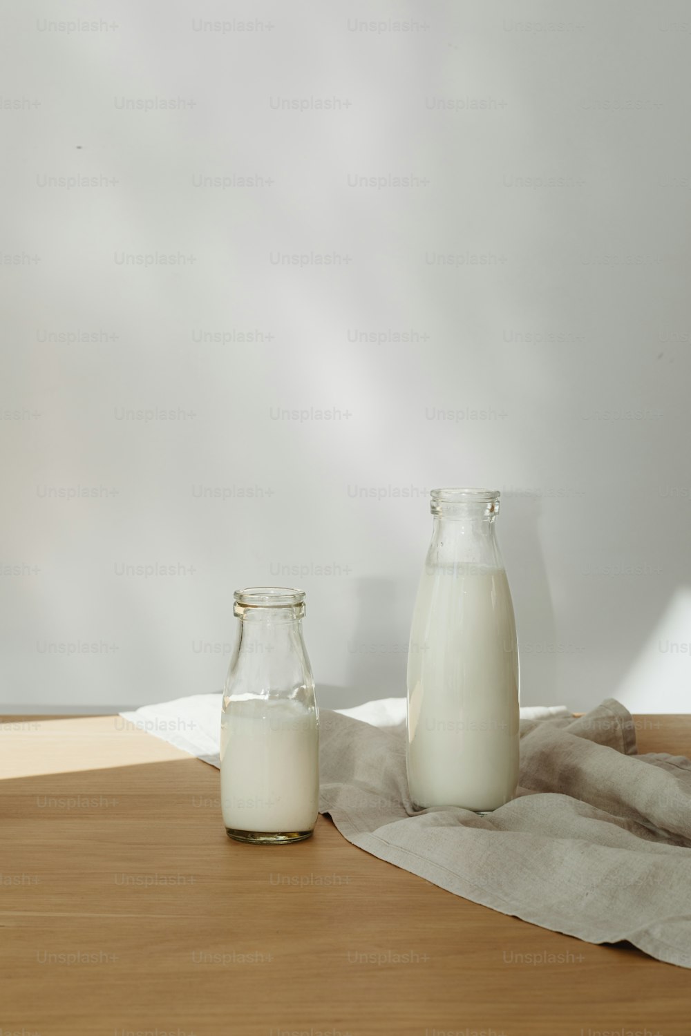 a wooden table topped with two bottles of milk