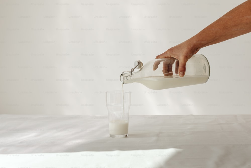 a person is pouring milk into a glass