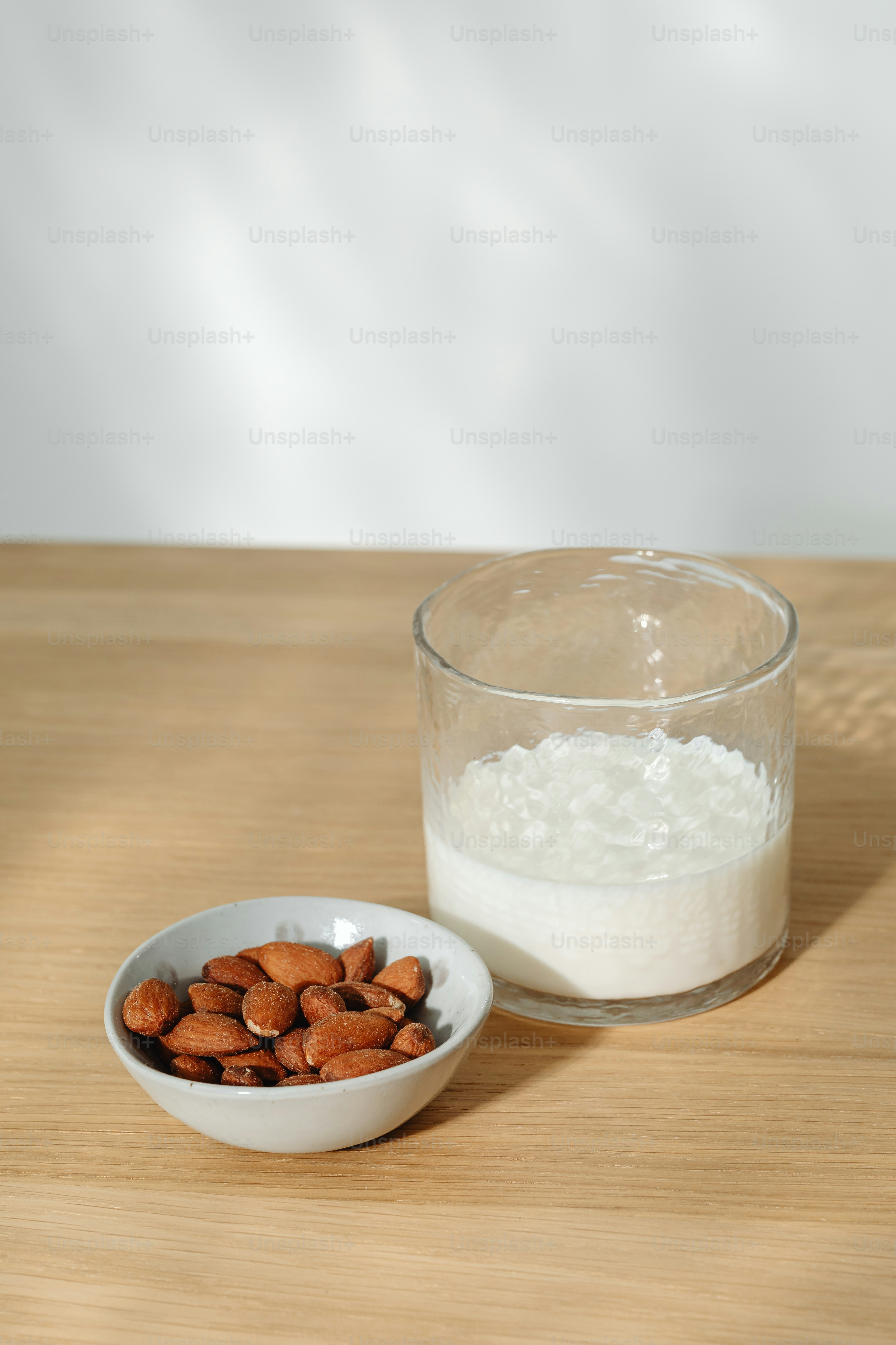 a bowl of almonds next to a glass of milk