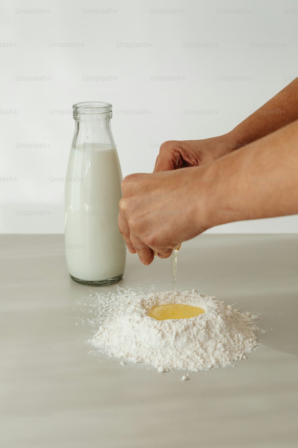 a bottle of milk being poured into a pile of flour