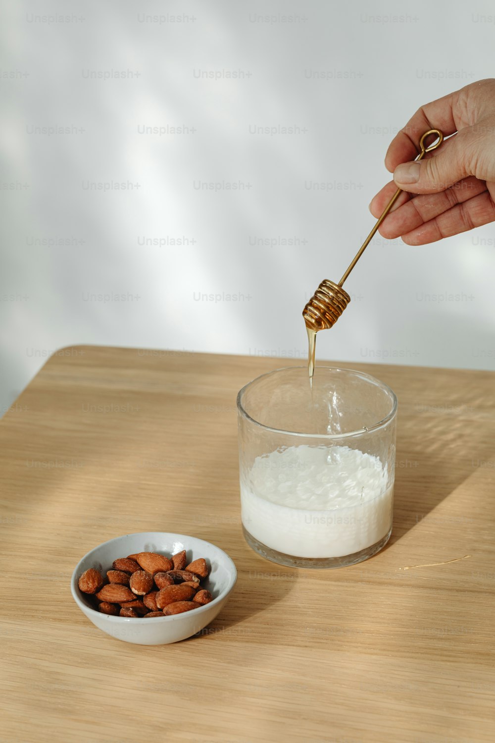 a person pouring sugar into a bowl of almonds